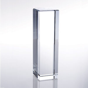 Crystal column award trophy standing upright on a light reflective surface, ideal for corporate or employee recognition.