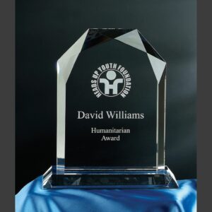 Crystal glass plaque with beveled edges on blue cloth, engraved for a humanitarian award recognizing outstanding achievement.