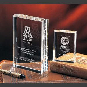 Crystal award trophies on leather desk, featuring UASV and ASE logos; ideal for corporate or employee recognition.