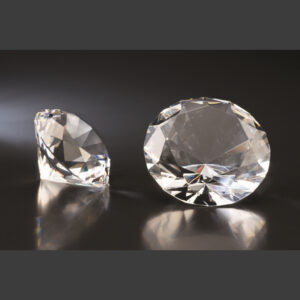 Clear crystal trophy awards on a dark reflective surface, upright and horizontal, ideal for corporate recognition or milestones.