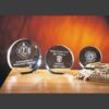 Crystal glass trophy awards with engraved names on wood surface, perfect for corporate or employee recognition events.