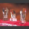 Crystal golf awards with faceted accents on red cloth, one personalized for Hugh Davis, ideal for corporate recognition.