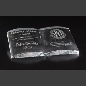 Crystal book-shaped award engraved with Industry Leader Award, recipient name, and SPCP logo on a dark background.