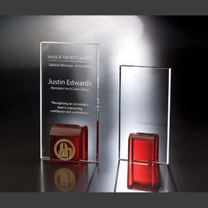 Crystal award trophies with red bases, engraved for corporate recognition and milestones, displayed on a dark background.