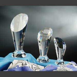 Crystal trophy awards of varying heights displayed on patterned cloth, ideal for corporate or employee recognition.