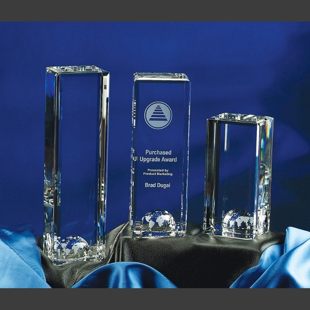 World Tower crystal awards with globe bases on black and blue satin, center piece engraved—ideal for corporate recognition.