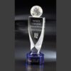 Crystal trophy with globe, engraved for corporate achievement, on blue base; etched names and reflective background.