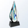 Teardrop crystal art glass award with blue, green, and yellow ribbons on black base; ideal for corporate recognition.