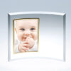 Crystal plaque featuring a baby portrait in a curved glass frame with gold border, displayed against a light background.