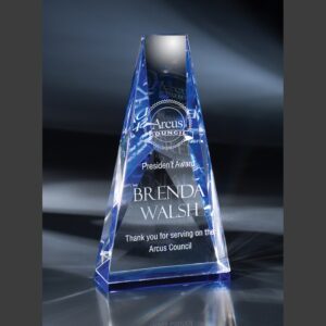 Blue crystal pyramid trophy recognizing dedicated service, displayed on a reflective base against a dark background.