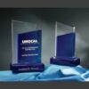 Bliss Crystal Award glass trophy with blue base for corporate recognition, displayed on a blue cloth.