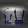 Crystal award trophies with blue accents, one engraved for corporate recognition, displayed against a dark background.