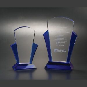 Crystal award trophies with blue accents, one engraved for corporate recognition, displayed against a dark background.