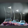 Crystal award trophies in varying heights displayed on fabric background, largest with engraved text for corporate or employee recognition.