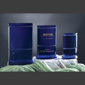 Blue crystal award trophies of varying heights on fabric, center with engraved corporate recognition text, clear glass material.