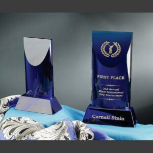 Blue crystal trophy set on patterned fabric, one engraved with “First Place” golf award and the name “Cornell Stein.”.