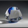 Geometric crystal trophy with clear and blue sections on gray surface, ideal for corporate awards or employee recognition.