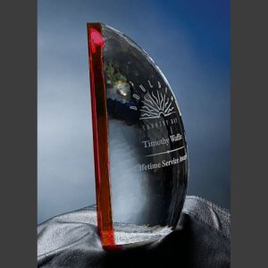 Crystal award with red edge, engraved for Lifetime Service, displayed on black cloth with blue gradient background.