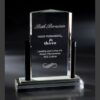 Crystal glass award plaque on black base, recognizing corporate achievement, presented against a dark background.